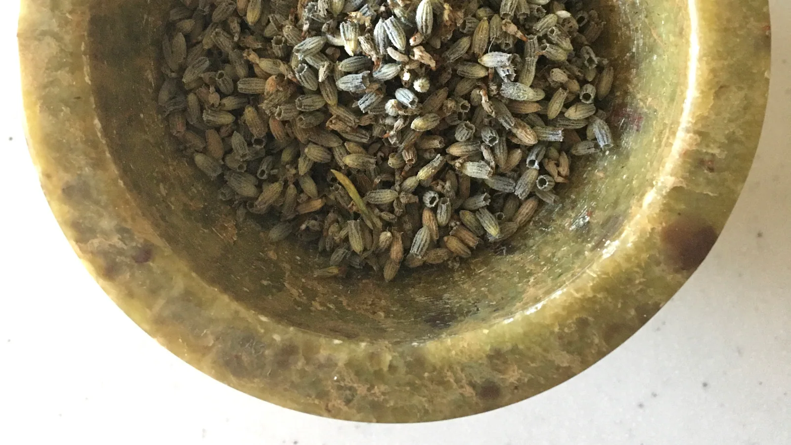 Capullos de lavanda seca en un cuenco de piedra, listos para moler